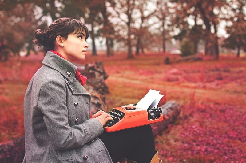 Young woman typing a blog post in the park